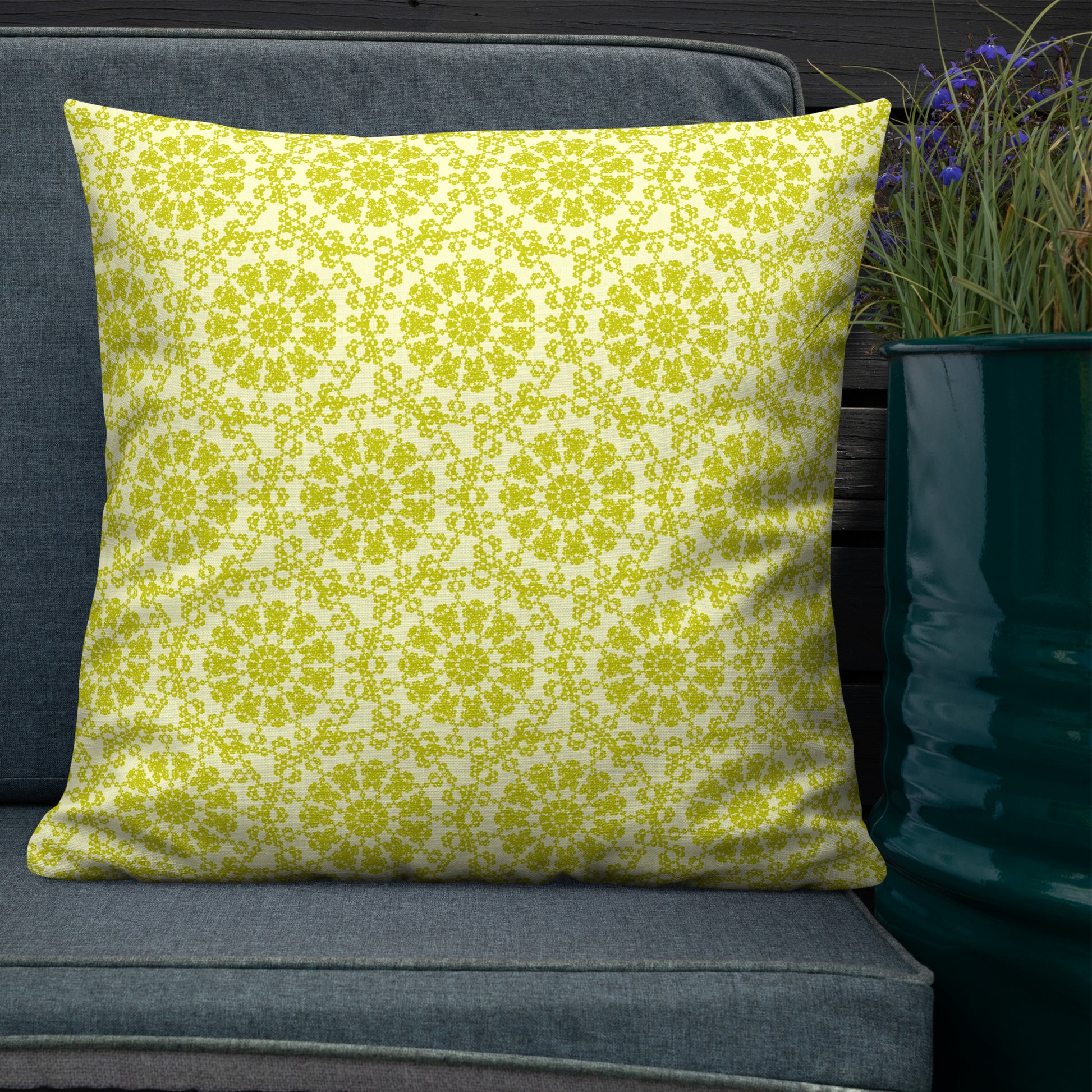 22″×22″ premium throw pillow with the 'Hendecagon' yellow-green geometric pattern on an outdoor sofa with teal planter