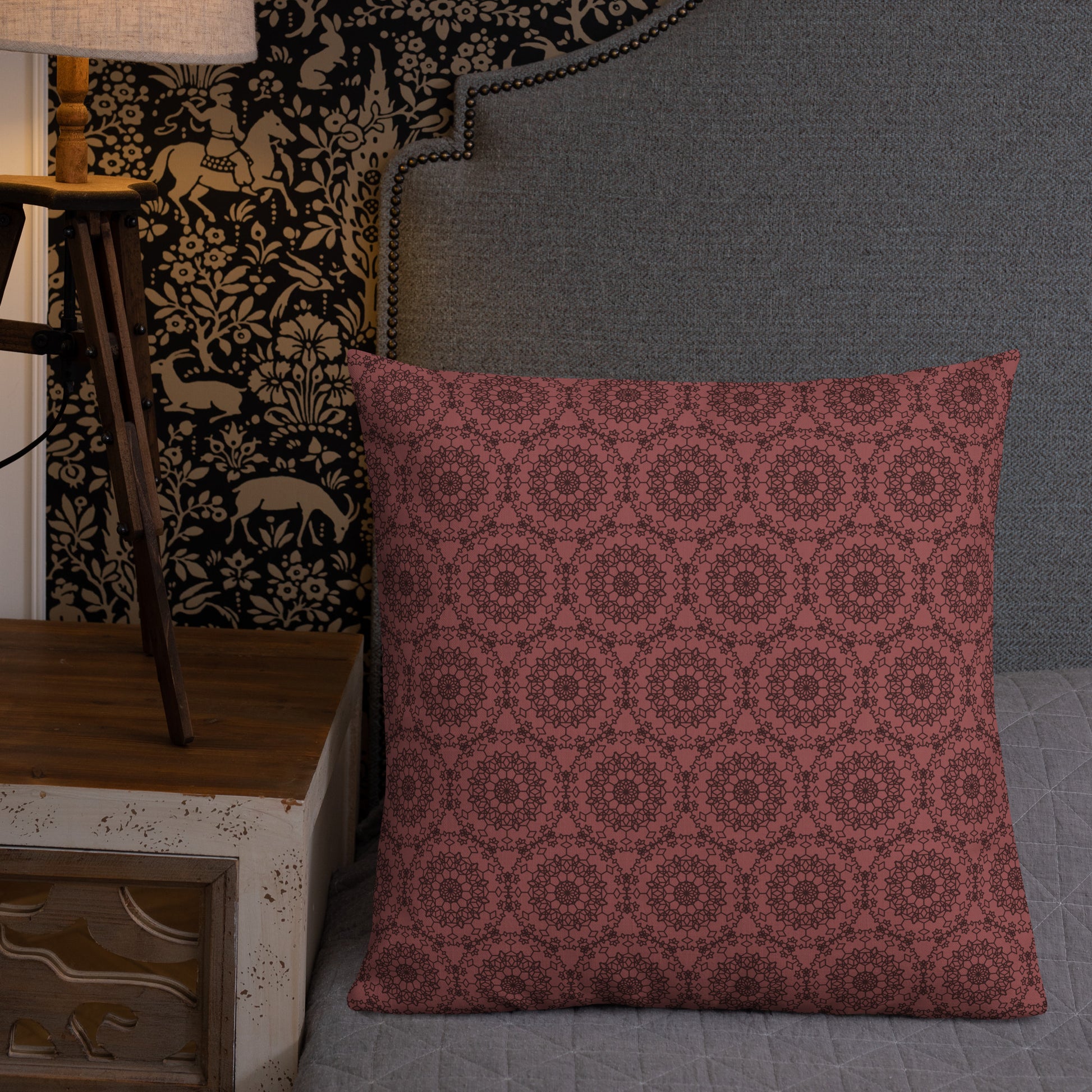 22″×22″ premium throw pillow with the 'Dodecagon' rose geometric pattern on bed beside grey upholstered headboard with lamp.