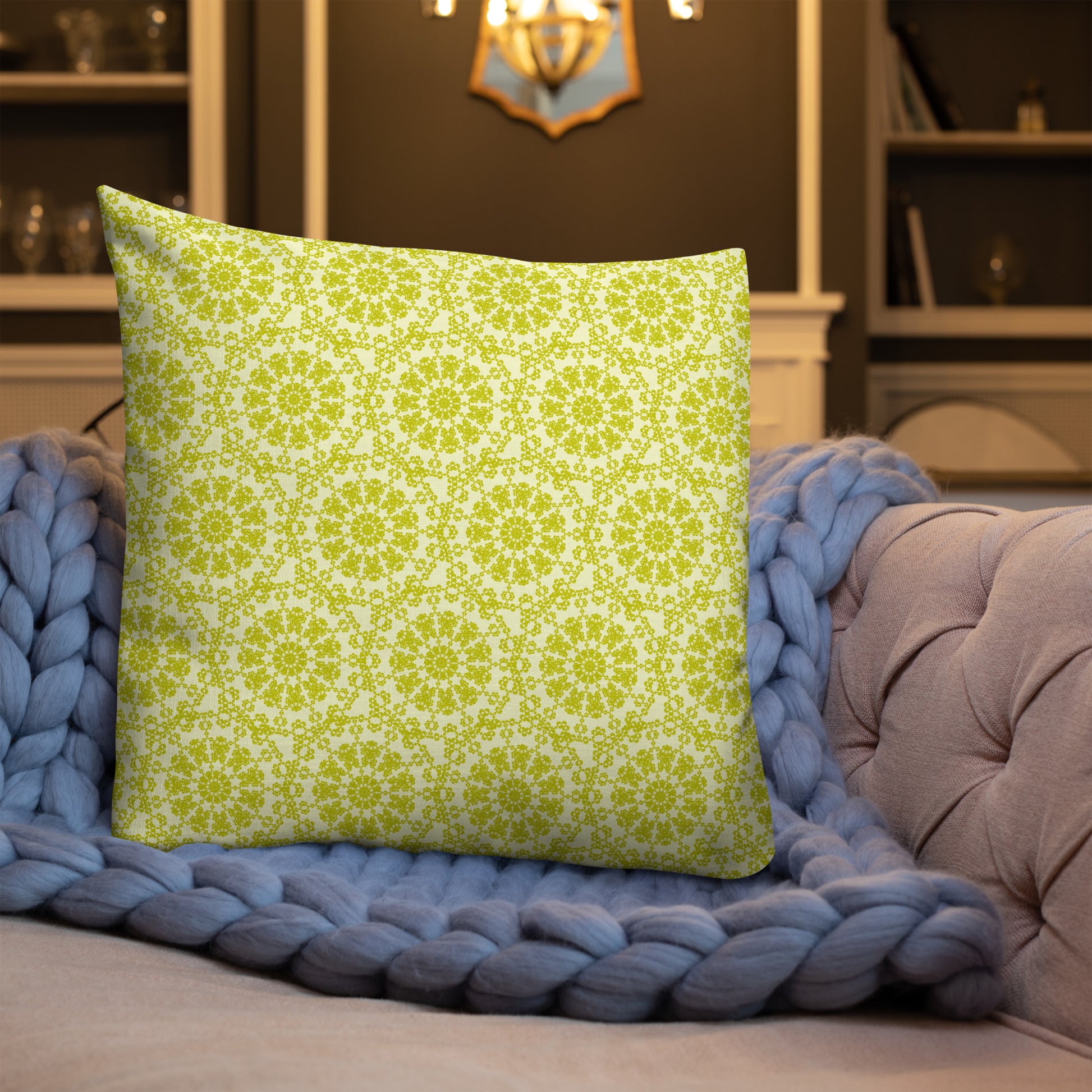 22″×22″ premium throw pillow with the 'Hendecagon' yellow-green geometric pattern on a sofa with chunky knit blanket