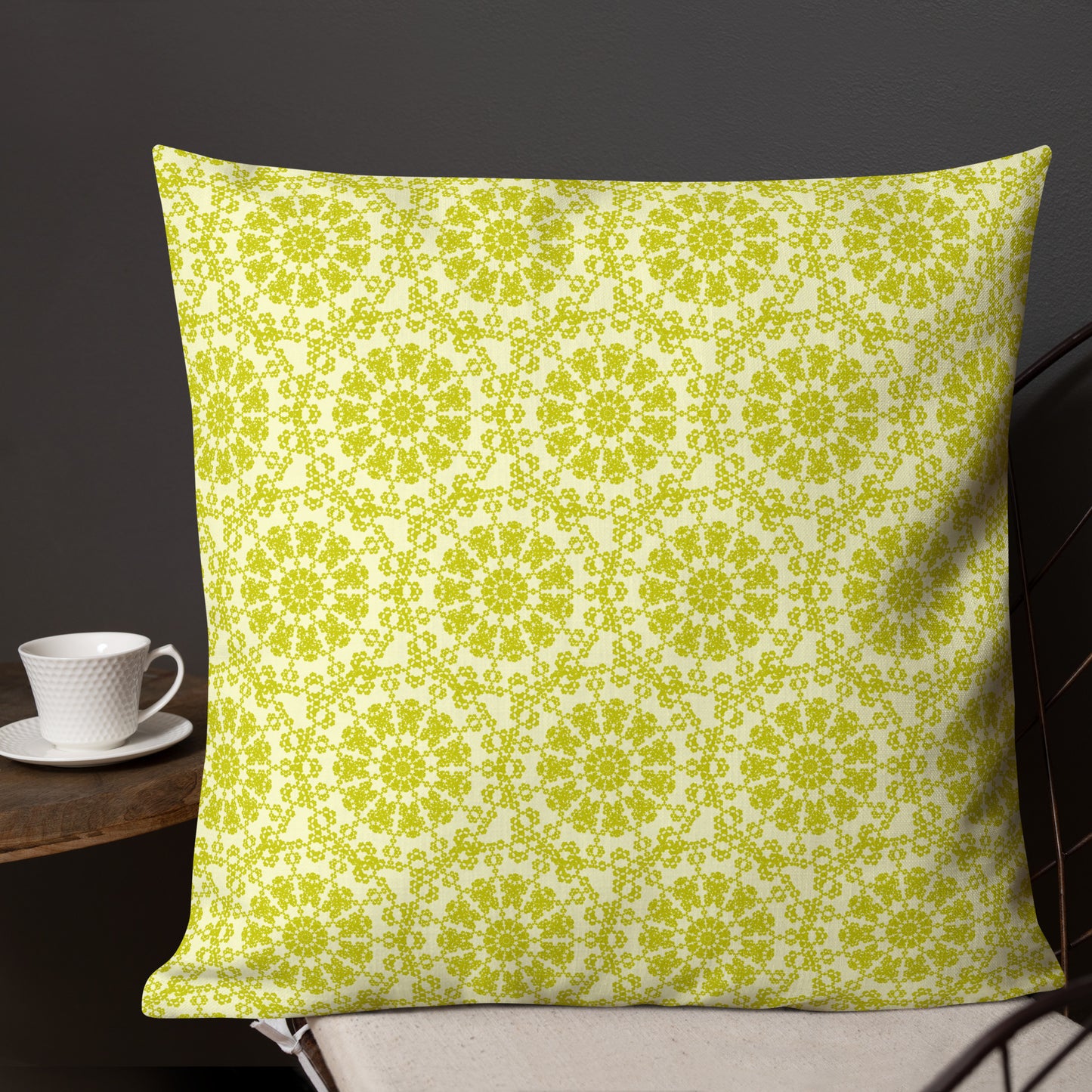 22″×22″ premium throw pillow with the 'Hendecagon' yellow-green geometric pattern on a wire chair with a side table