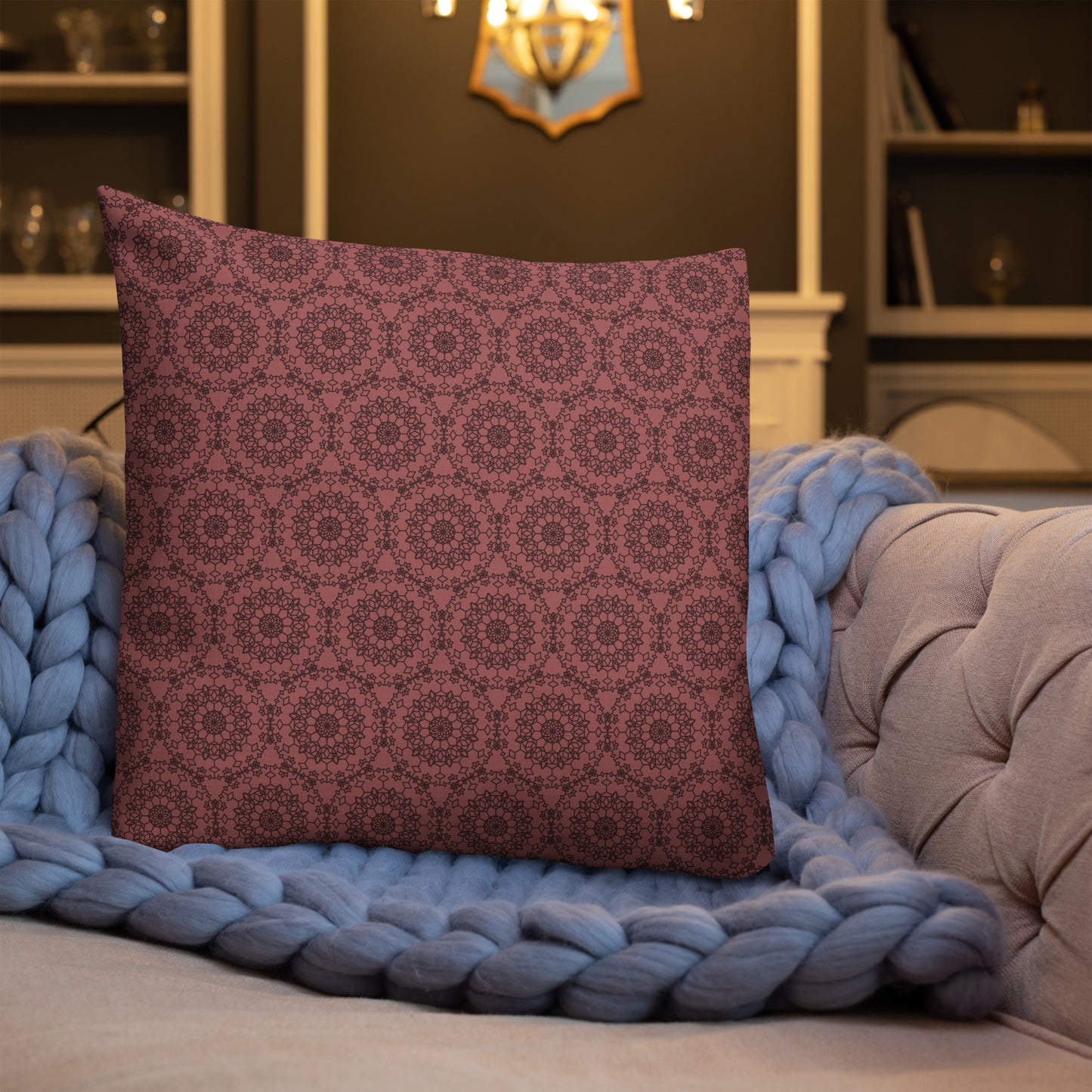 22″×22″ premium throw pillow with the 'Dodecagon' rose geometric pattern on tufted sofa with chunky blue knit blanket.
