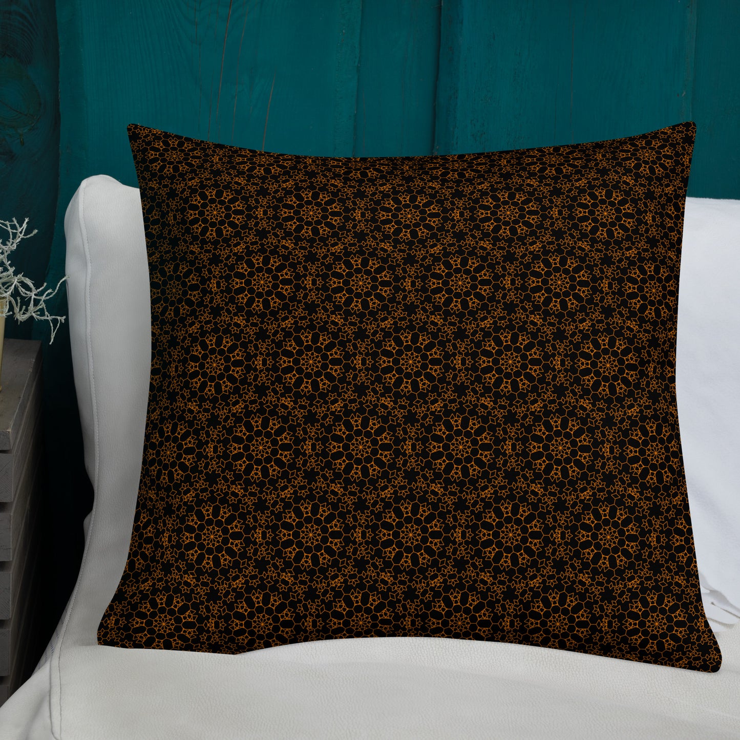 22″×22″ premium throw pillow with the 'Enneagon' black & gold geometric pattern on a bed with white bedding and teal wall.