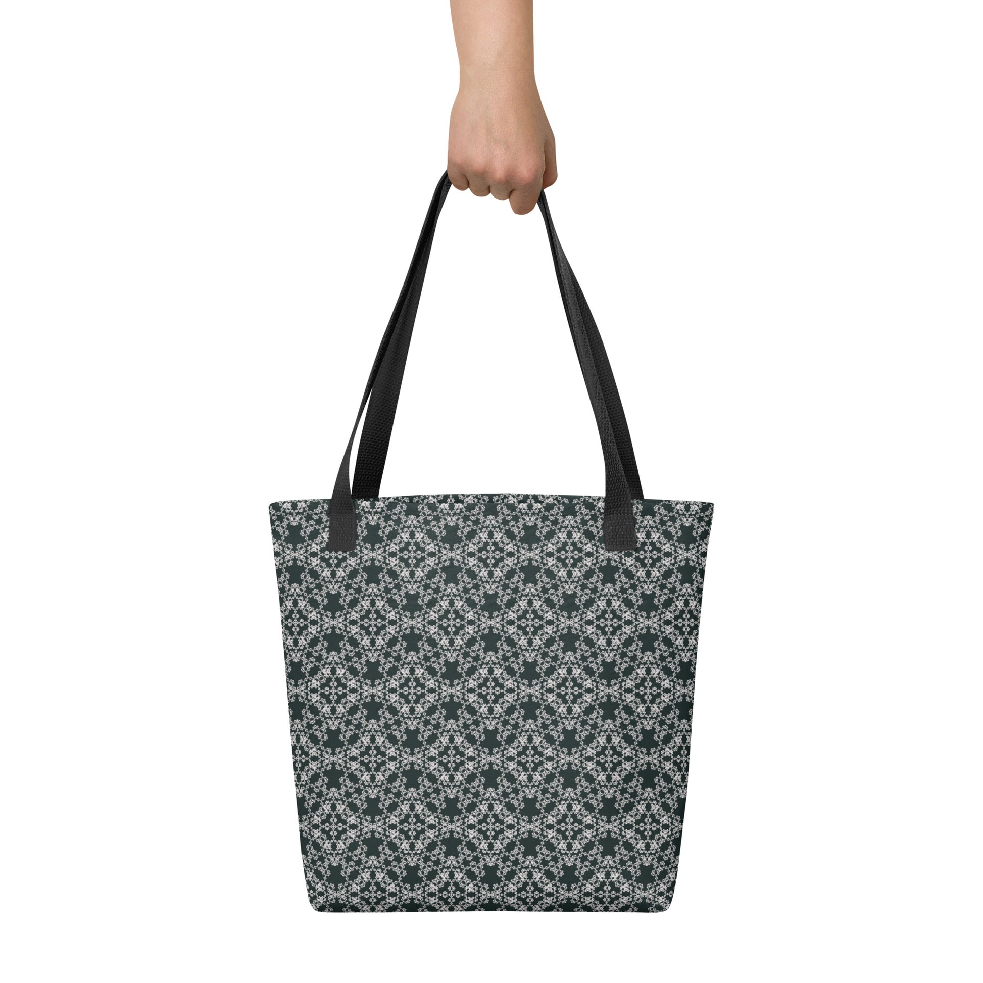 Hand holding the tote bag with the 'Quadragon' charcoal and white fractal geometric pattern.