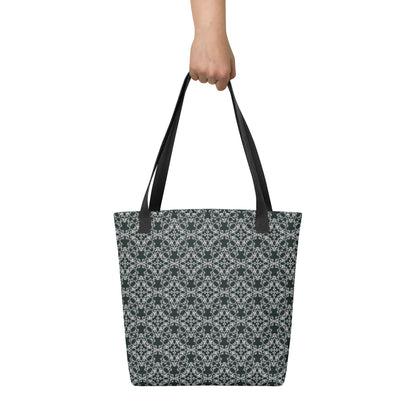 Hand holding the tote bag with the 'Quadragon' charcoal and white fractal geometric pattern.