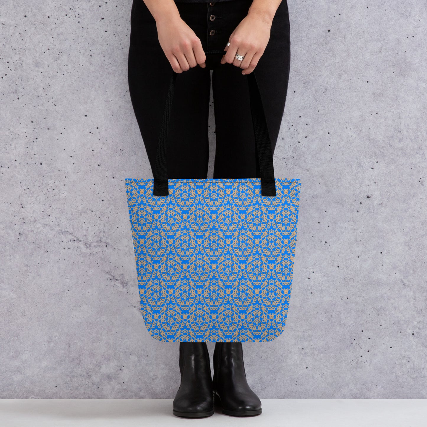 Close up of the lower part of a model holding with two hands the tote bag with the 'Pentagon' blue and yellow fractal geometric pattern.