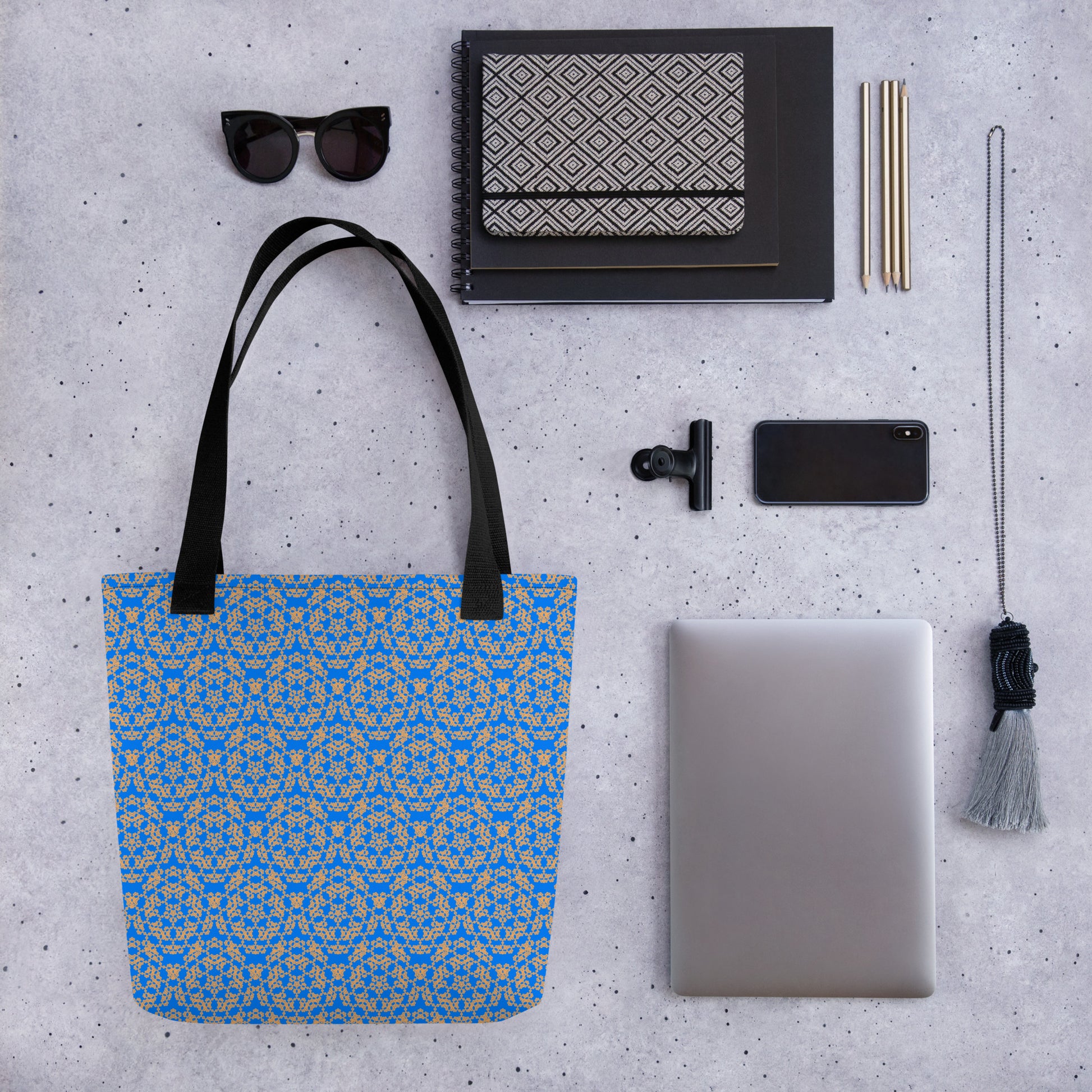 Close up of various objects placed beside the tote bag with the 'Pentagon' blue and yellow fractal geometric pattern.