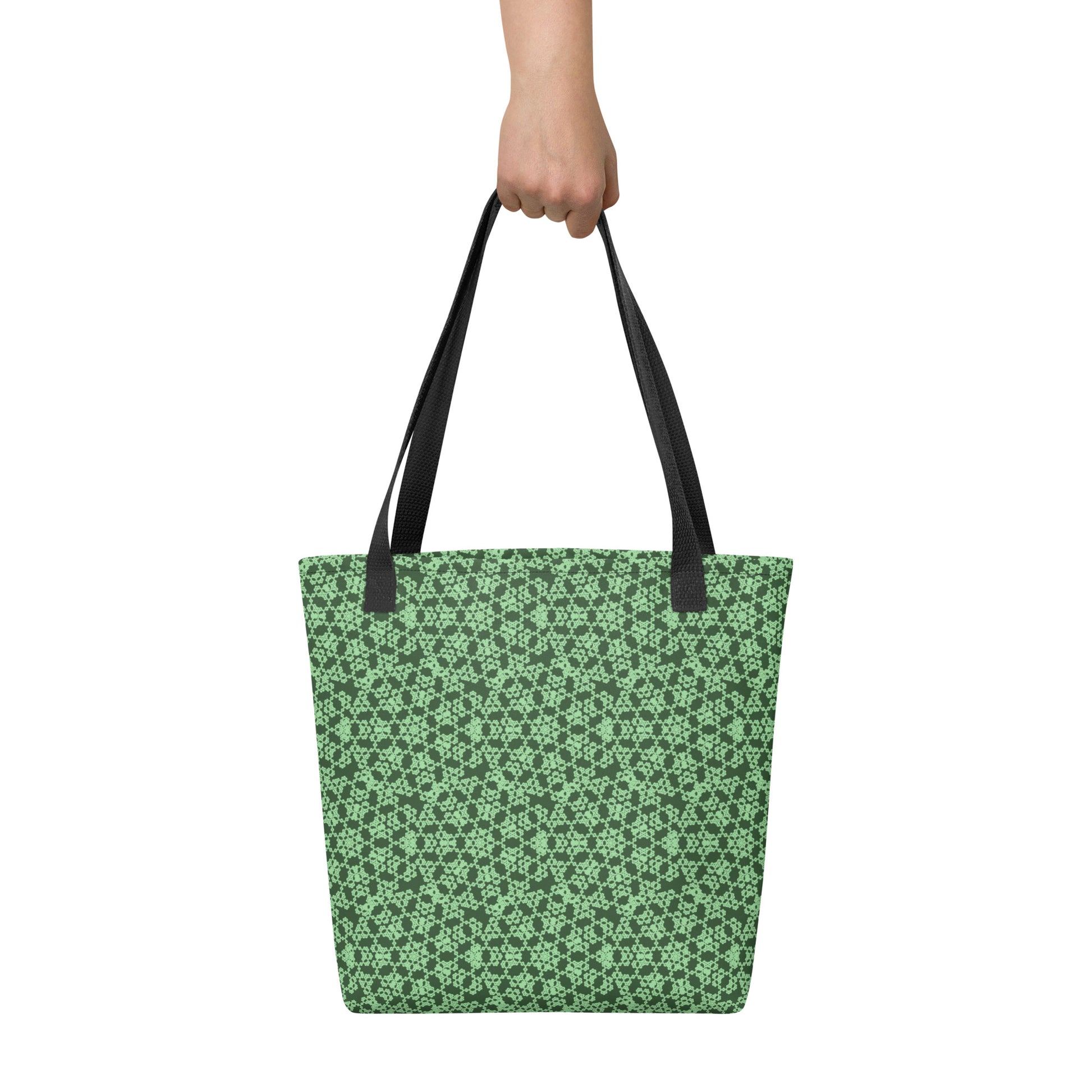 Hand holding the tote bag with the 'Heptagon' green fractal geometric pattern.