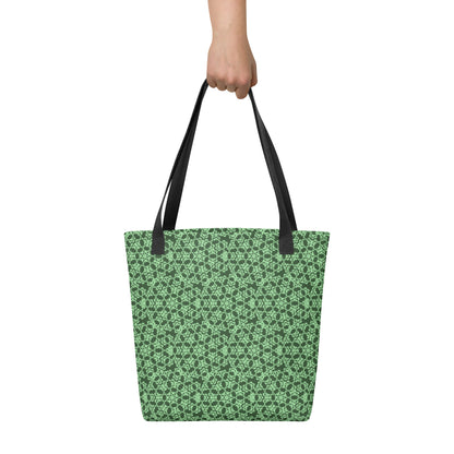 Hand holding the tote bag with the 'Heptagon' green fractal geometric pattern.