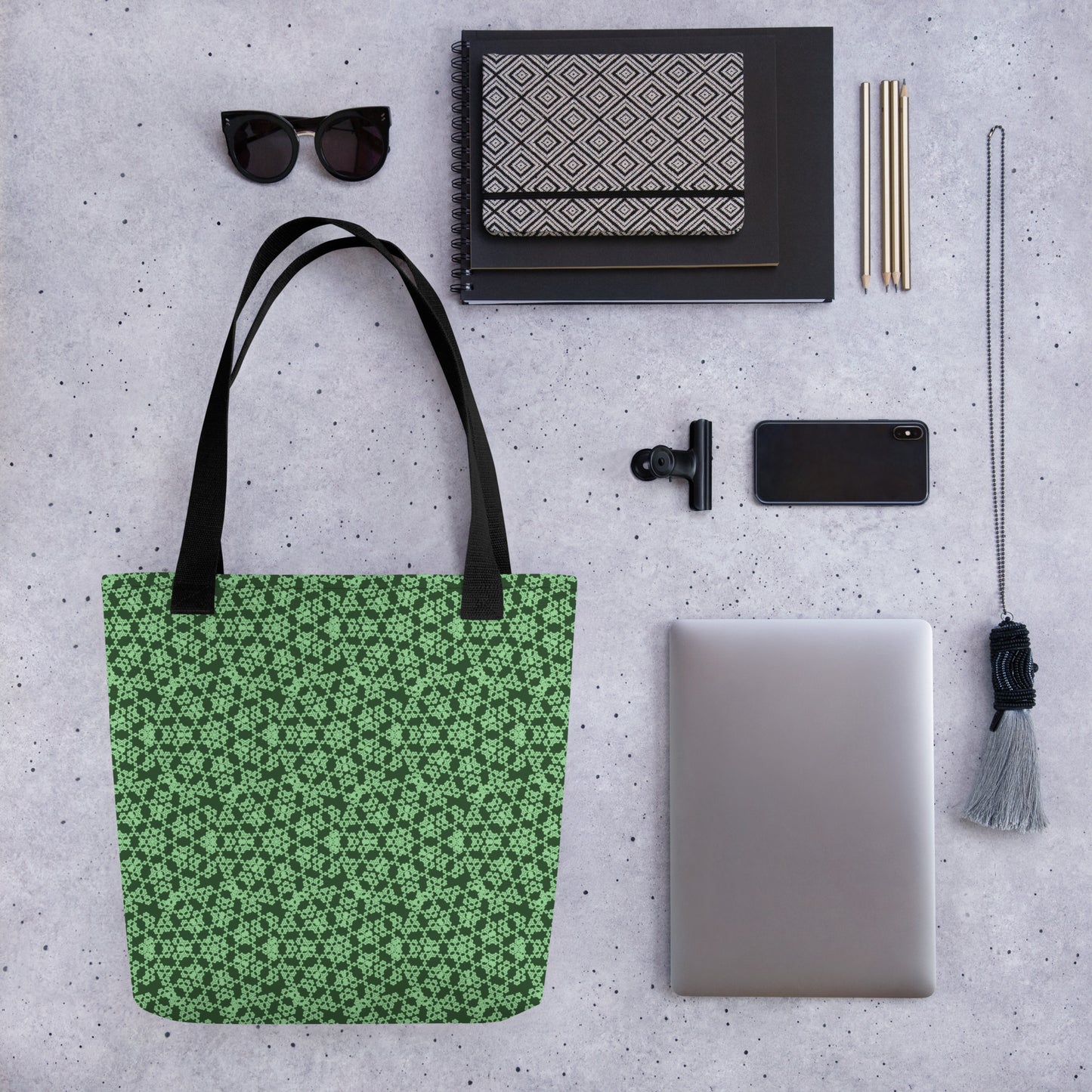 Close up of various objects placed beside the tote bag with the 'Heptagon' green fractal geometric pattern.