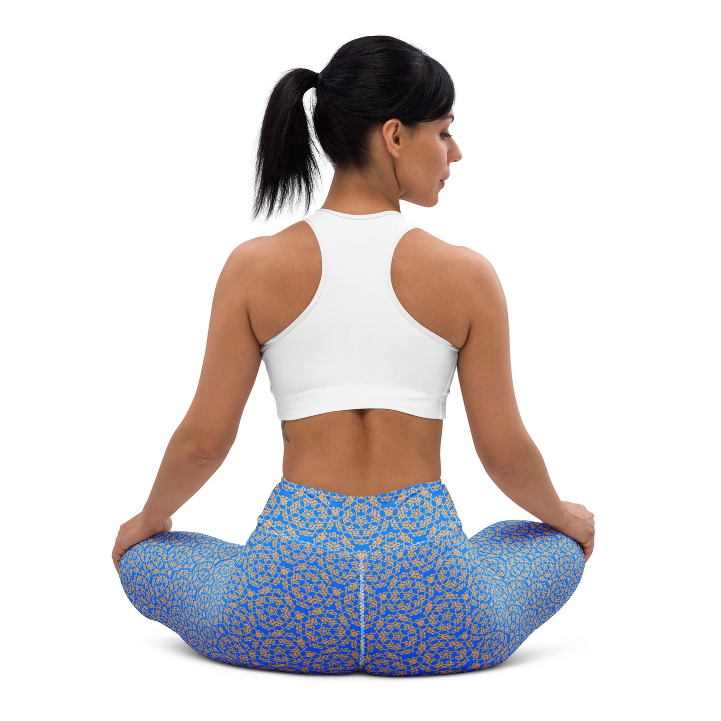 Back shot of a young woman sitting in lotus position wearing leggings with the 'Pentagon' blue and yellow fractal geometric pattern.