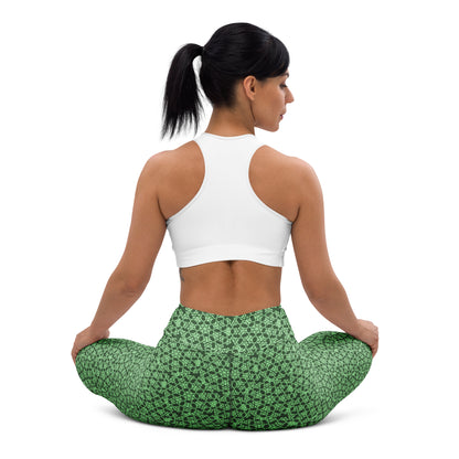 Back shot of a young woman sitting in lotus position wearing leggings with the 'Heptagon' green fractal geometric pattern.