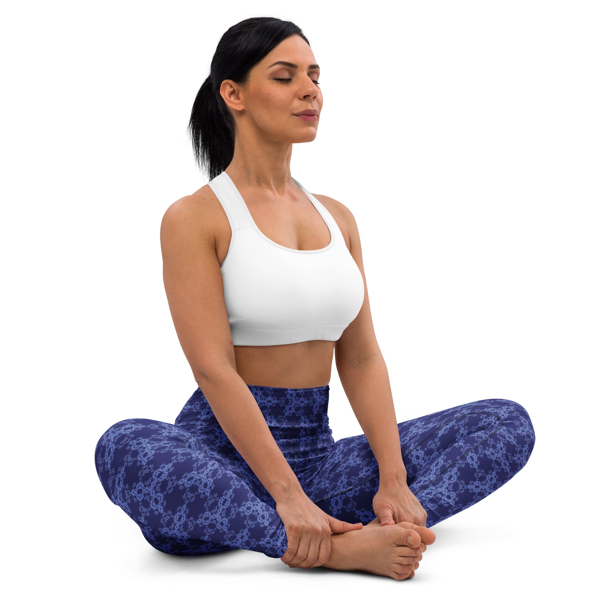 Young woman sitting in lotus position wearing leggings with the 'Triagon' navy and blue fractal geometric pattern.