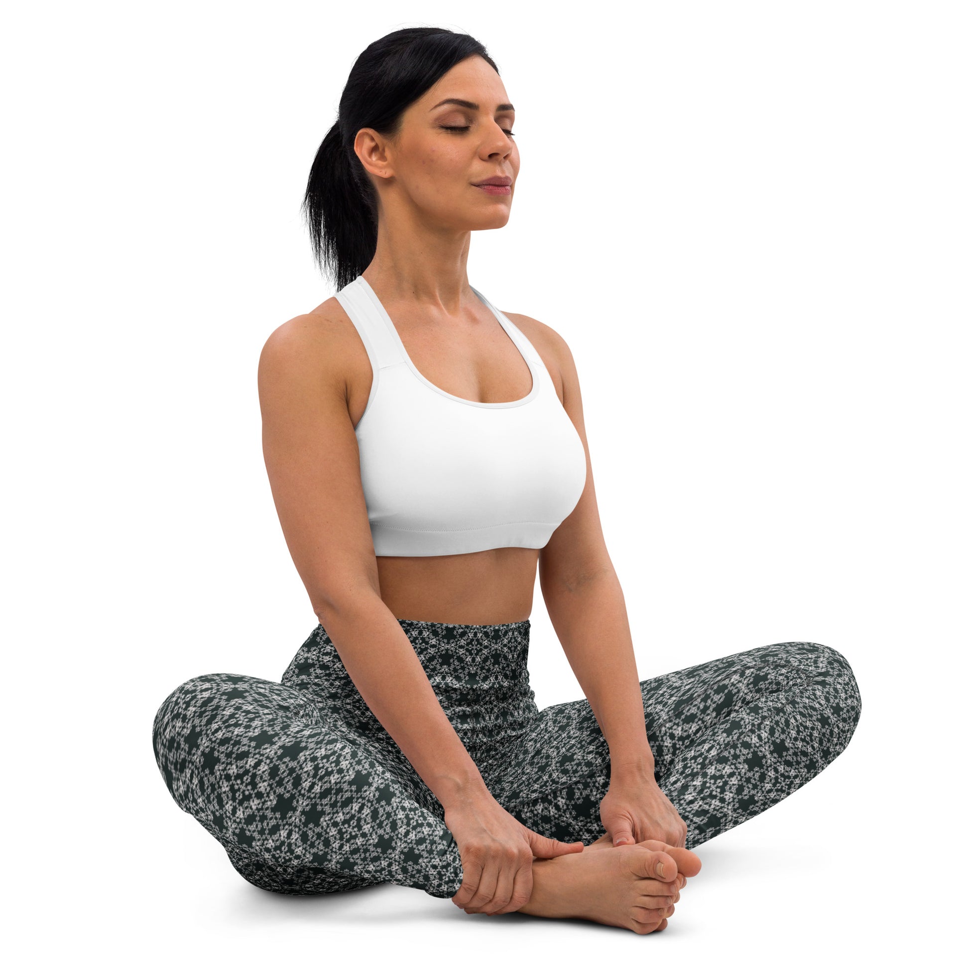 Young woman sitting in lotus position wearing leggings with the 'Quadragon' charcoal and white fractal geometric pattern.