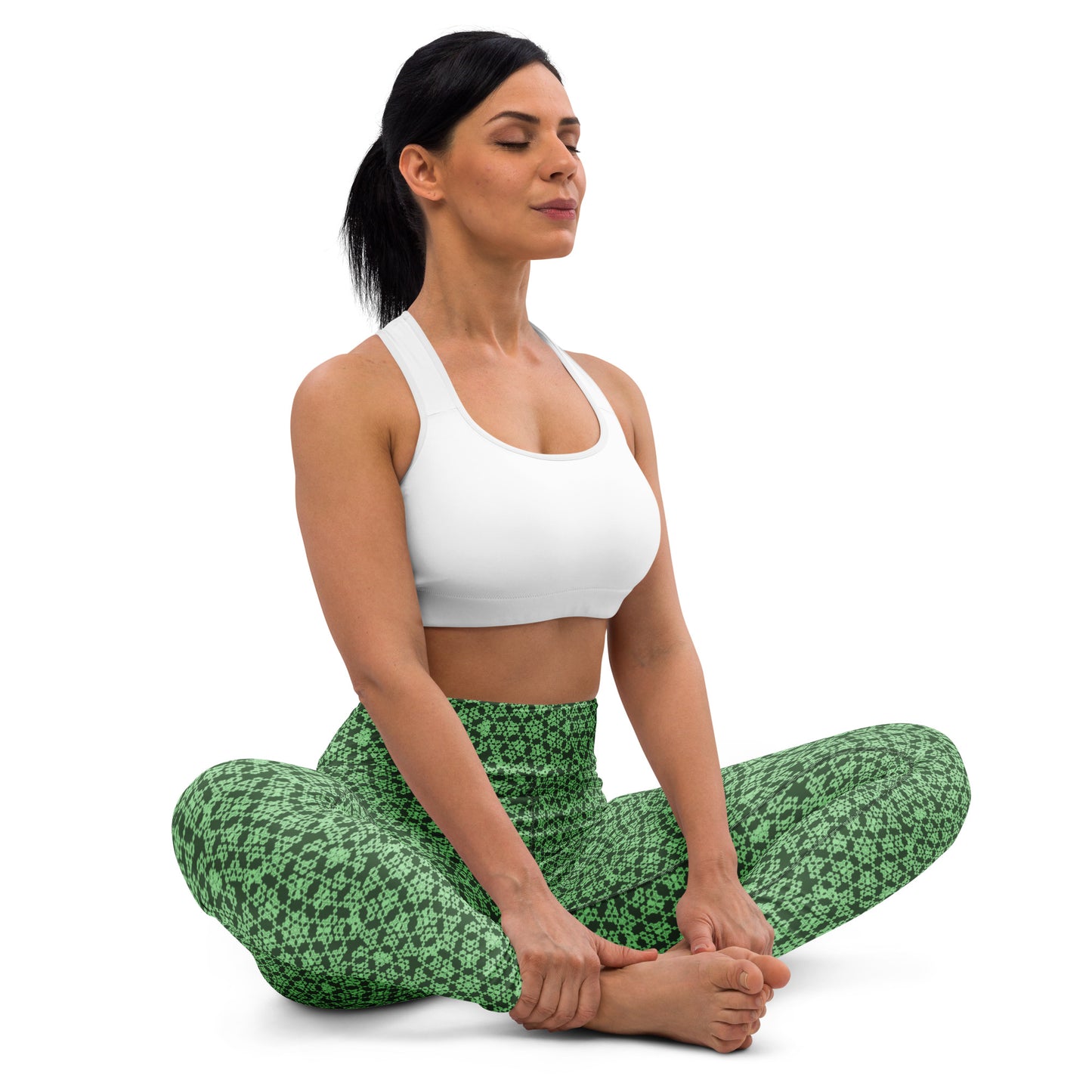 Young woman sitting in lotus position wearing leggings with the 'Heptagon' green fractal geometric pattern.