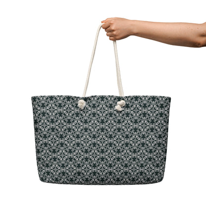 Hand holding the oversized weekender bag with the 'Quadragon' charcoal and white fractal geometric pattern.